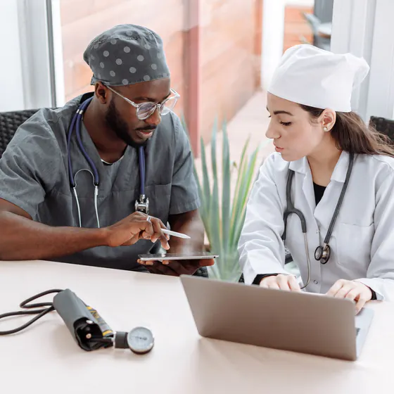 Deux professionnels de santé coordonnant leur activité sur une tablette et un ordinateur portable