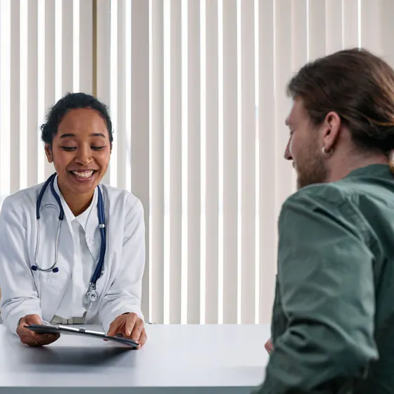 Médecin généraliste souriante en consultation avec un patient dans son cabinet