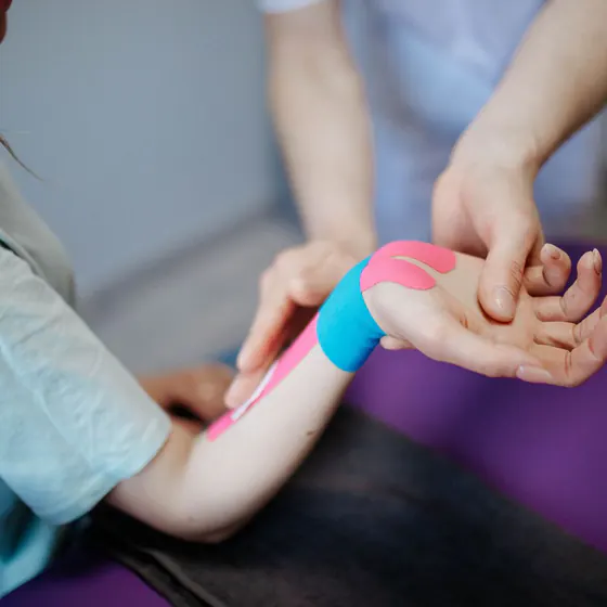 Kinésithérapeute posant une bande de taping sur le poignet d'un patient